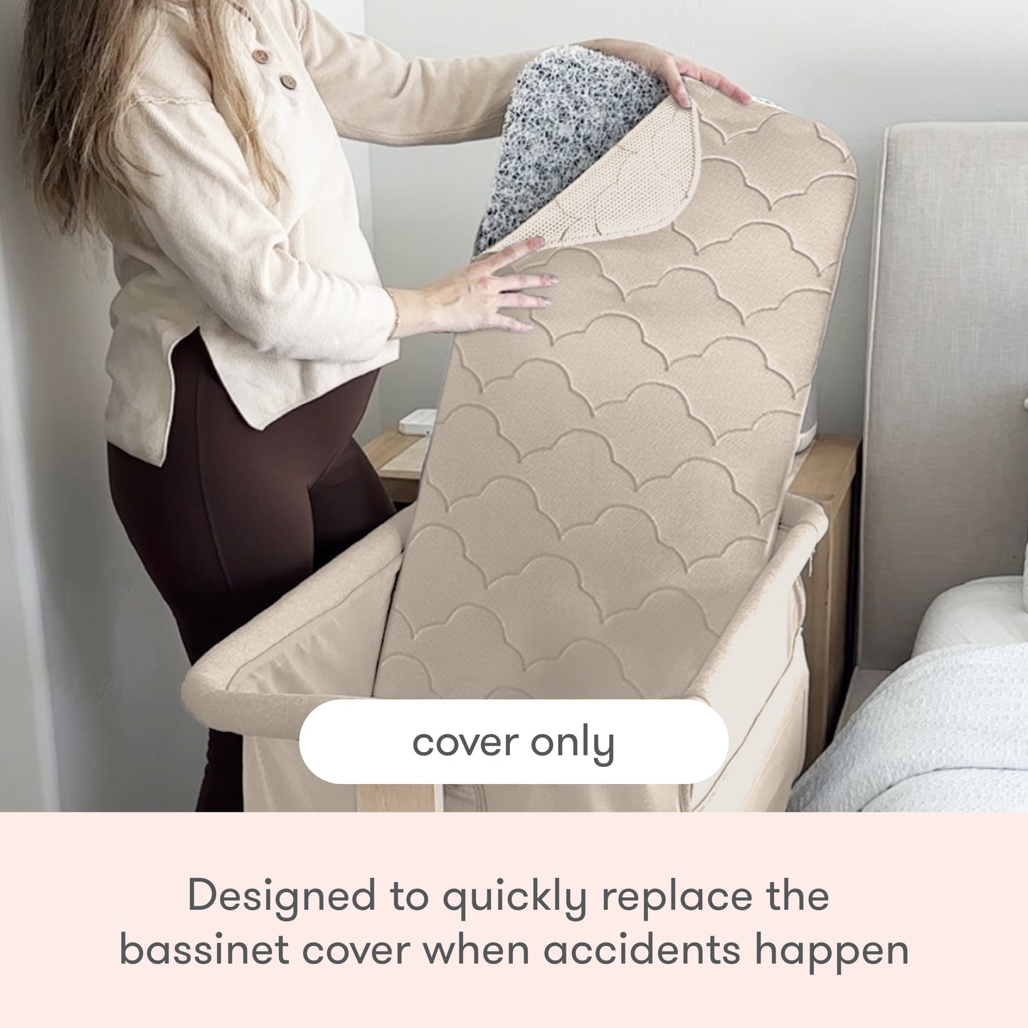 A person lifts a beige, quilted Newton Baby Extra Bassinet Mattress Cover to reveal its speckled underside beside a bed. Text reads: “cover only” and “Easily replace the Bassinet Mattress Cover after accidents. Machine washable.”.