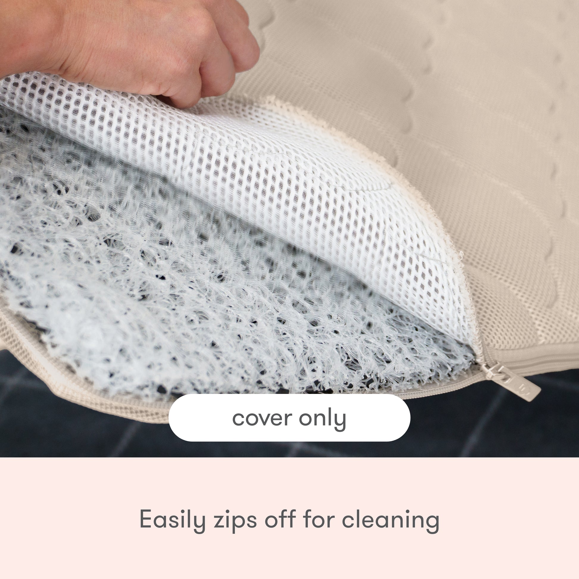 A hand unzips the Newton Baby Extra Bassinet Mattress Cover, revealing a white mesh layer. Text says cover only—easily zips off for cleaning and is machine washable for convenience.