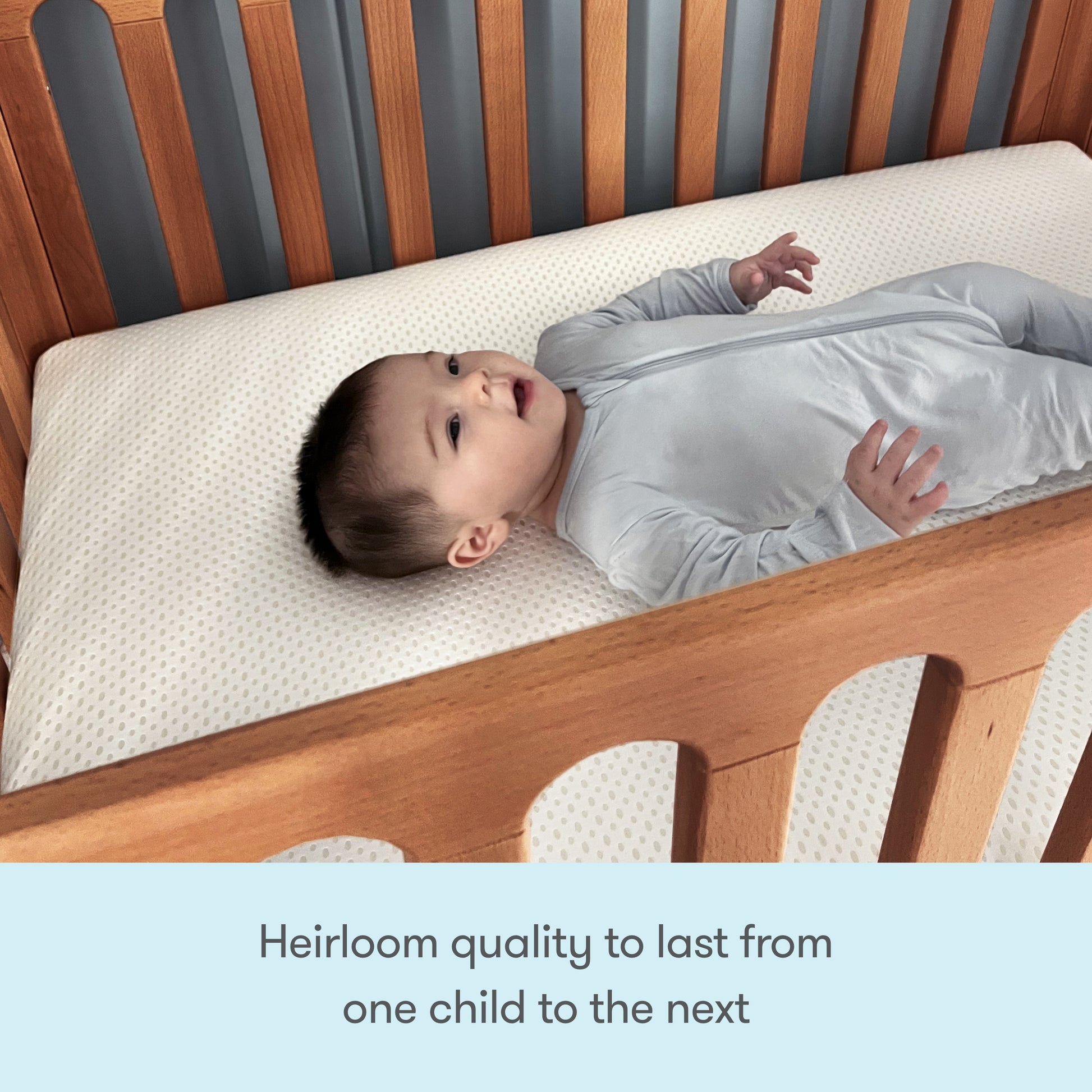 A baby in a light gray onesie lies on a Newton Galileo Mini Crib with Newton Mattress by Newton Baby. Text below reads: Heirloom quality to last from one child to the next.