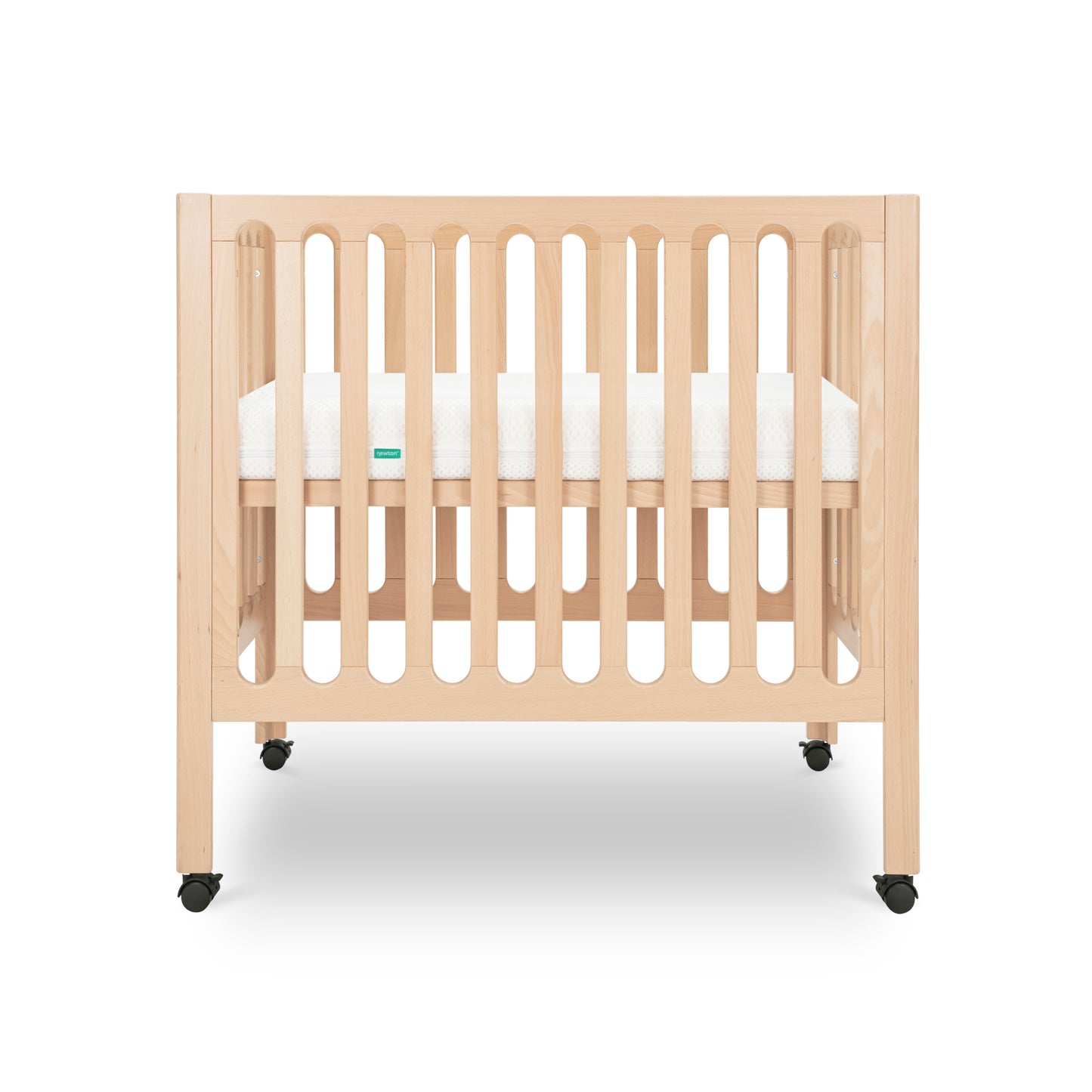 The Newton Baby Galileo Mini Crib with Newton Mattress features beech wood, vertical slats, a white mattress, and four black caster wheels for portability, shown against a white background.