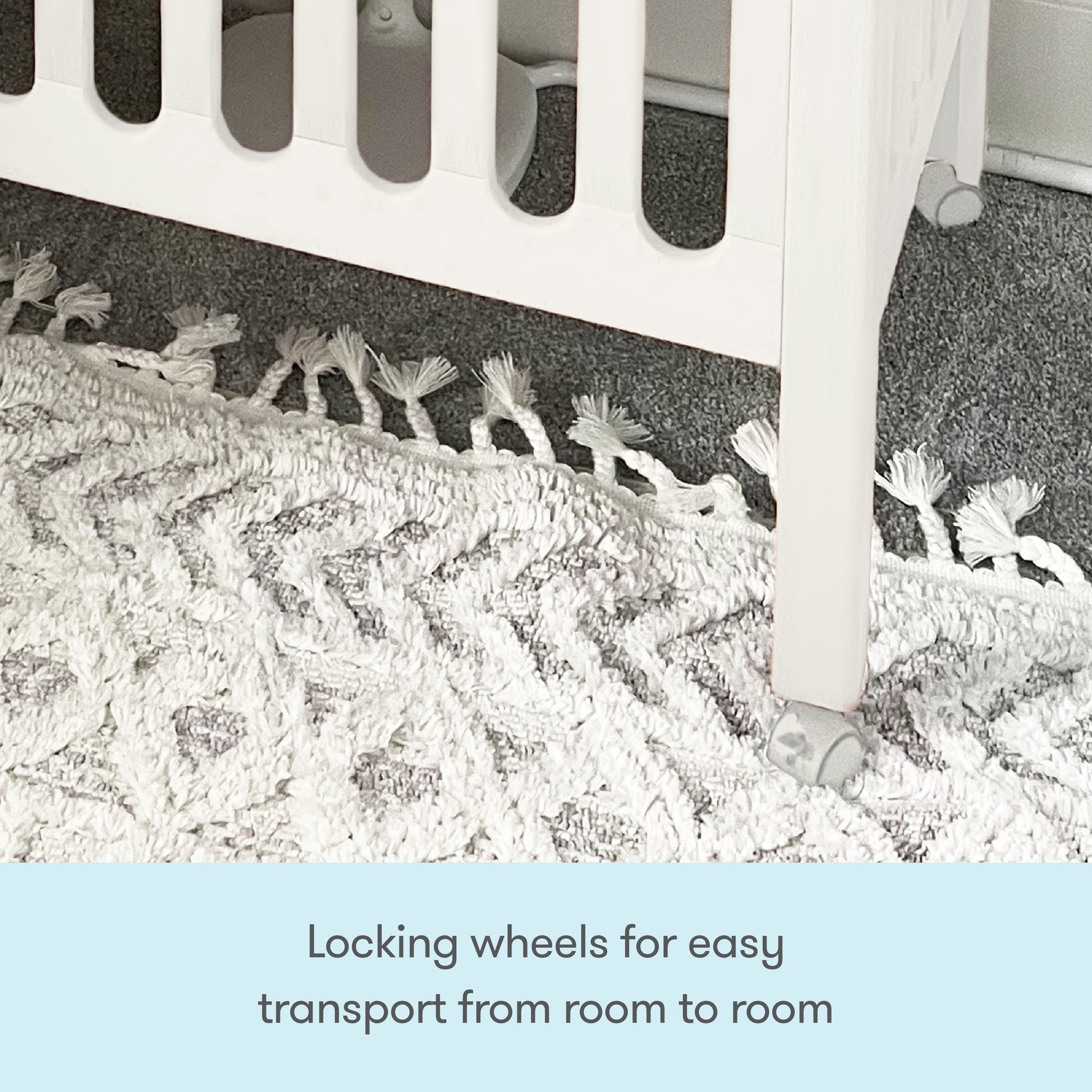 Close-up of the Newton Galileo Mini Crib with Newton Mattress by Newton Baby, showing its locking wheels on a textured white and gray rug. Text below: Locking wheels allow easy transport from room to room.