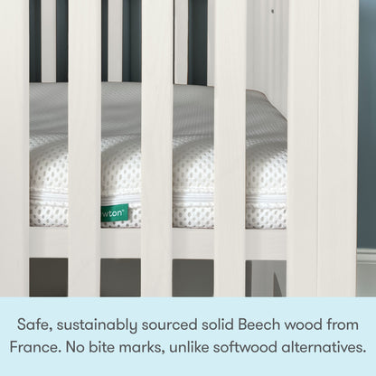 Close-up of a white Newton Galileo Mini Crib with Newton Mattress. Text below reads: Crafted from safe, sustainably sourced solid Beech wood from France—no bite marks like softwood alternatives. From Newton Baby.