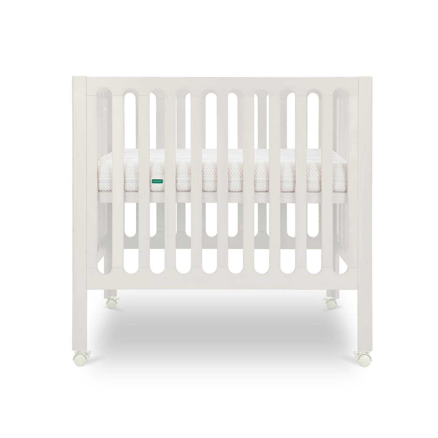 The Newton Baby Galileo Mini Crib with Newton Mattress is shown from the front, featuring white vertical slats, a mattress inside, and wheels for easy mobility against a plain white background.