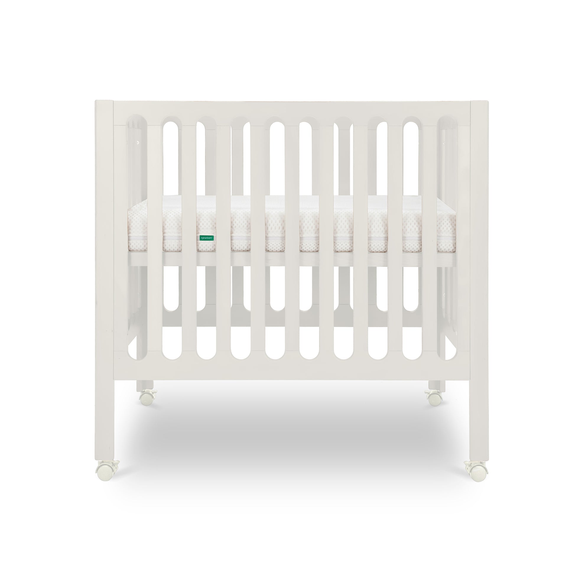 The Newton Baby Galileo Mini Crib with Newton Mattress is shown from the front, featuring white vertical slats, a mattress inside, and wheels for easy mobility against a plain white background.