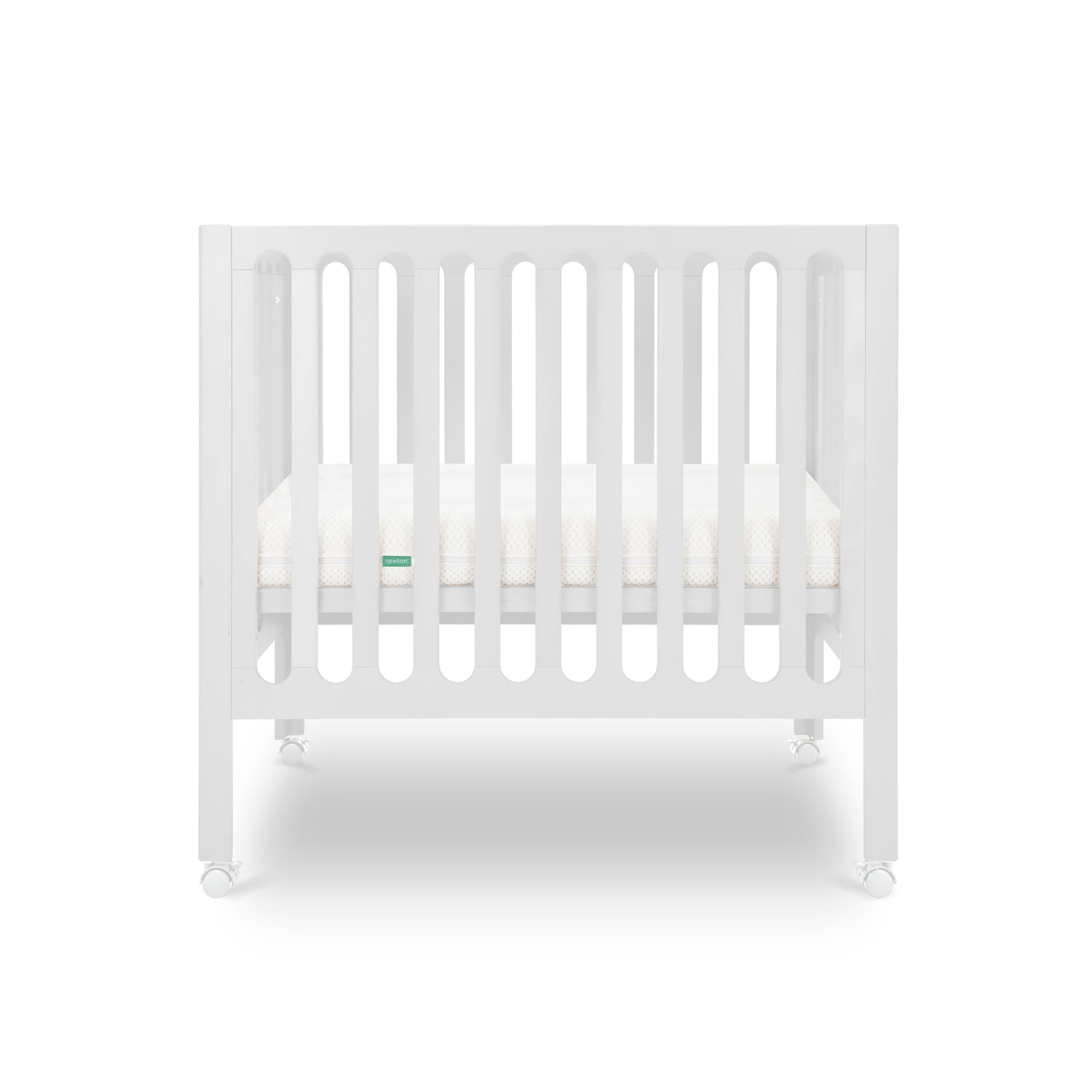 The Newton Baby Galileo Mini Crib with Newton Mattress features vertical slats, a comfy mattress, and four wheels. Crafted from durable beech wood, this portable white crib appears against a clean white background.
