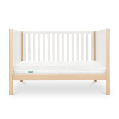 The Newton Galileo Convertible Crib by Newton Baby features natural beech wood legs, white slatted sides, and a white mattress. This 3-in-1 crib’s sleek, minimal design makes it ideal for any modern nursery.