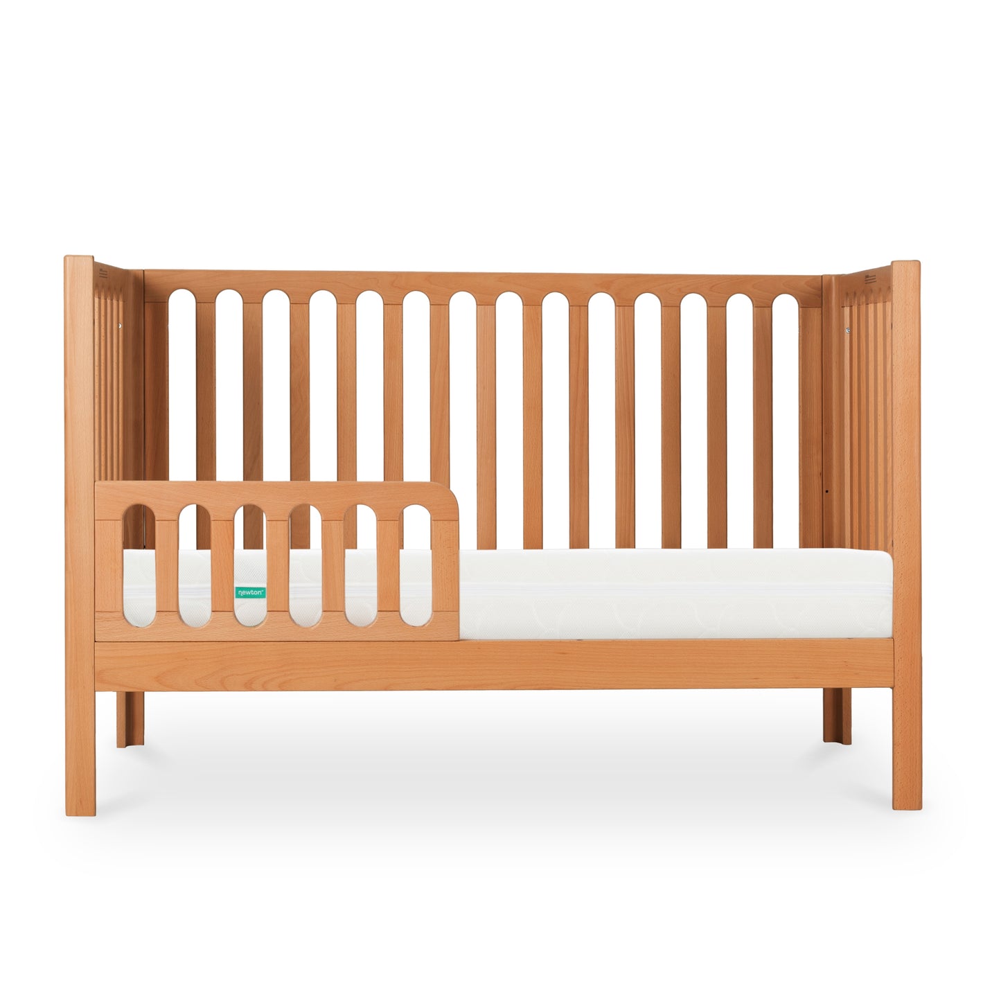 The Newton Galileo Convertible Crib by Newton Baby is a beech wood crib with vertical slats, featuring a partial guardrail and white mattress. Shown in toddler bed mode, it’s photographed against a white background.
