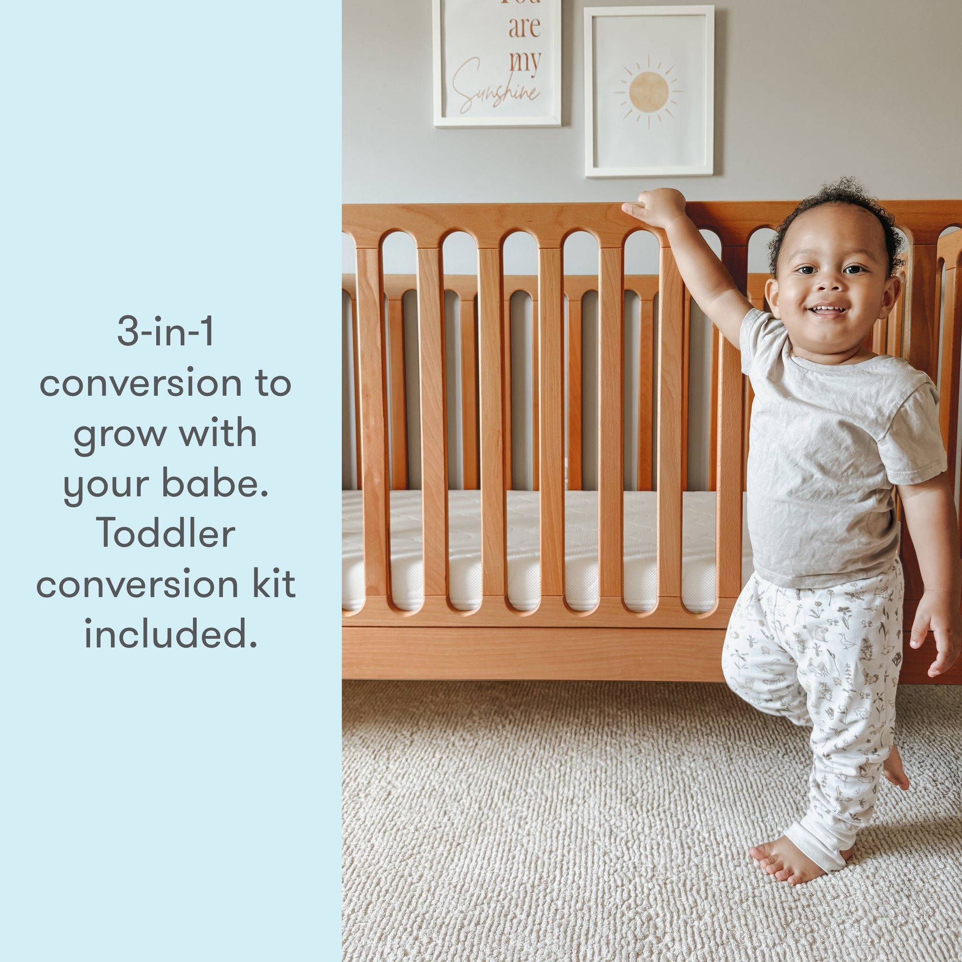 Toddler smiling next to a crib with text "3-in-1 conversion to grow with your babe. Toddler conversion kit included."