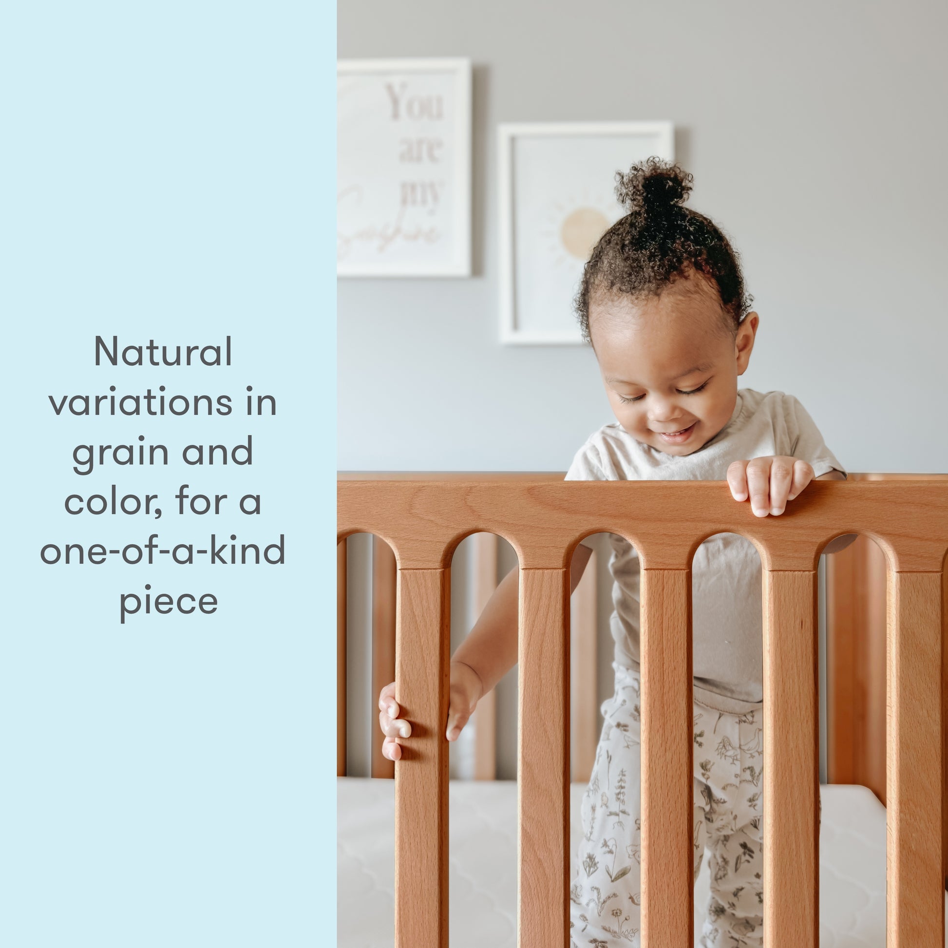 Toddler smiling while standing in a crib with the text "Natural variations in grain and color, for a one-of-a-kind piece".