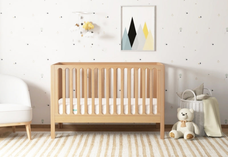 galileo crib in natural color, in nursery with newton mattress, front facing angle 999-8420-NAT