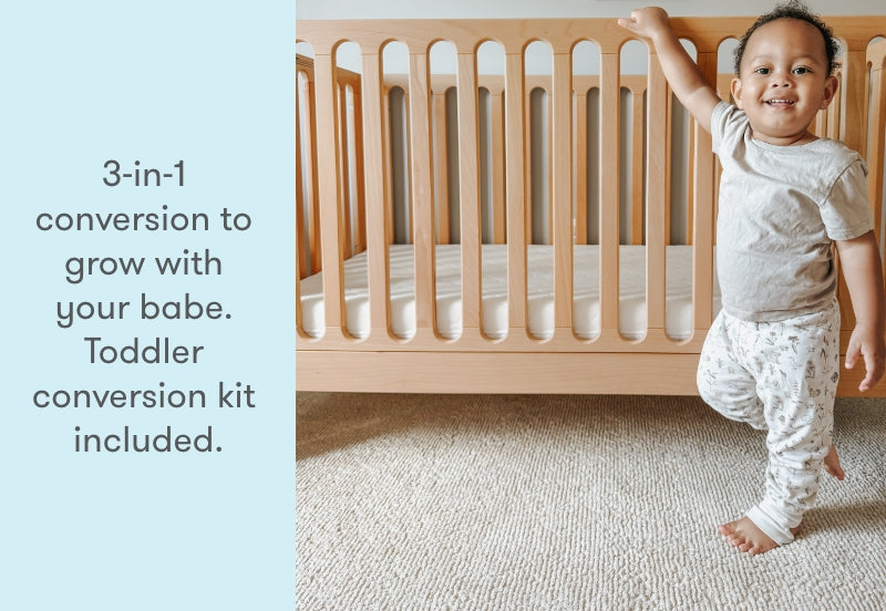 toddler standing next to newton galileo crib in natural color, text reads "3-in-1 conversion to grow with your babe. Toddler conversion kit included."