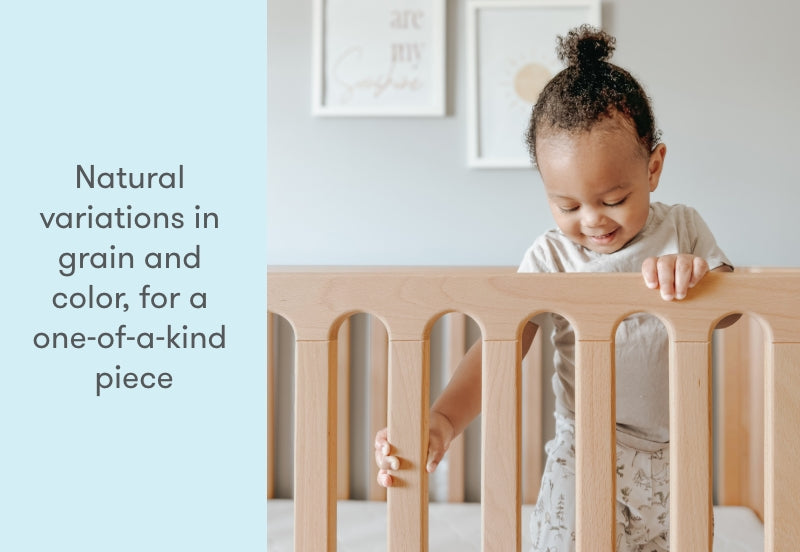 toddler standing up in newton galileo crib in natural color, text reads "natural variations in grain nd color, for a one-of-a-kind piece"