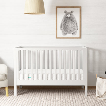 A serene nursery featuring a white wooden crib, white rug, and a bear painting on the wall, decorated with a minimalist art and a gentle color palette. 999-8420-WHT