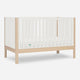 The Newton Galileo Convertible Crib by Newton Baby features natural beech wood legs and white slatted sides, displayed against a plain white background.