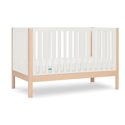 The Newton Galileo Convertible Crib by Newton Baby features natural beech wood legs, white slatted sides, a minimalist design, includes a white mattress, and converts to a toddler bed for long-lasting use.