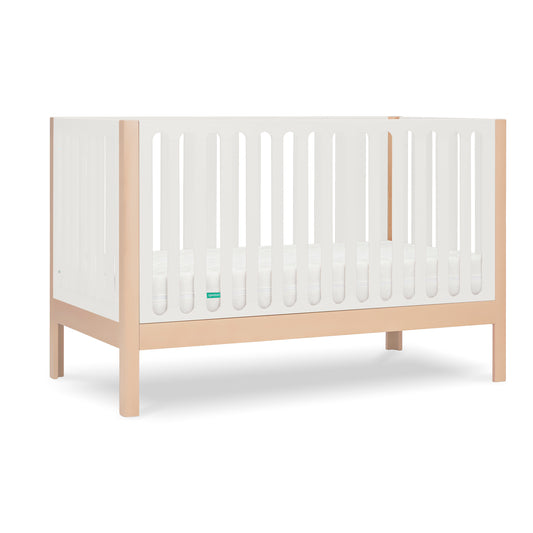 The Newton Galileo Convertible Crib by Newton Baby features natural beech wood legs, white slatted sides, a minimalist design, includes a white mattress, and converts to a toddler bed for long-lasting use.