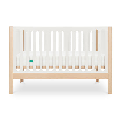 The Newton Galileo Convertible Crib by Newton Baby features a modern beech wood design with white slatted sides, includes a mattress, and easily converts to a toddler bed as your child grows.