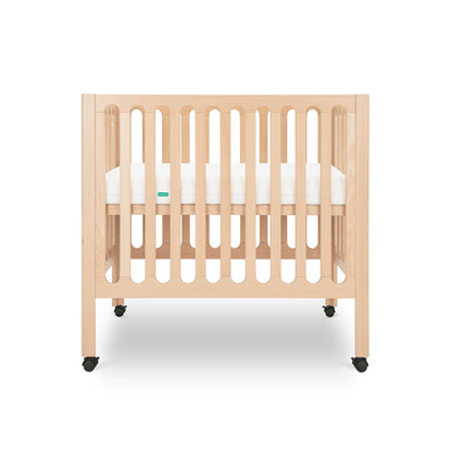 Modern wooden baby crib on wheels, featuring a white mattress and minimalist design.