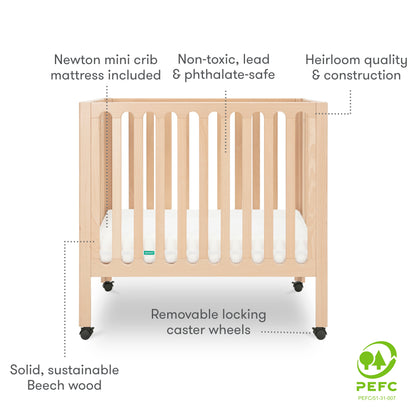 Newton mini crib made of solid, sustainable Beech wood, featuring non-toxic, lead & phthalate-safe materials, heirloom quality construction, removable locking caster wheels, and includes a mattress; certified by PEFC for sustainable forestry.