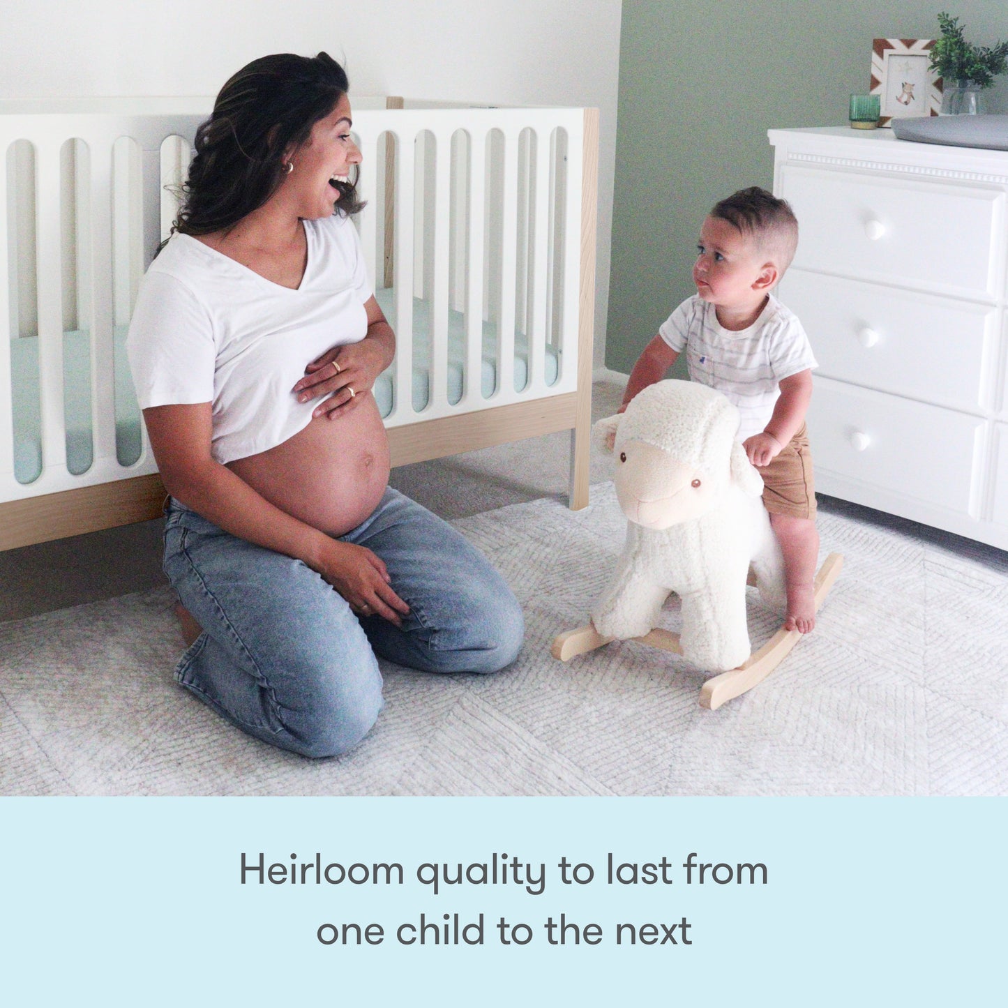 A pregnant woman smiles at a toddler riding a white plush rocking sheep in a softly lit nursery featuring the Newton Galileo Convertible Crib by Newton Baby. Text below reads, Heirloom quality to last from one child to the next.