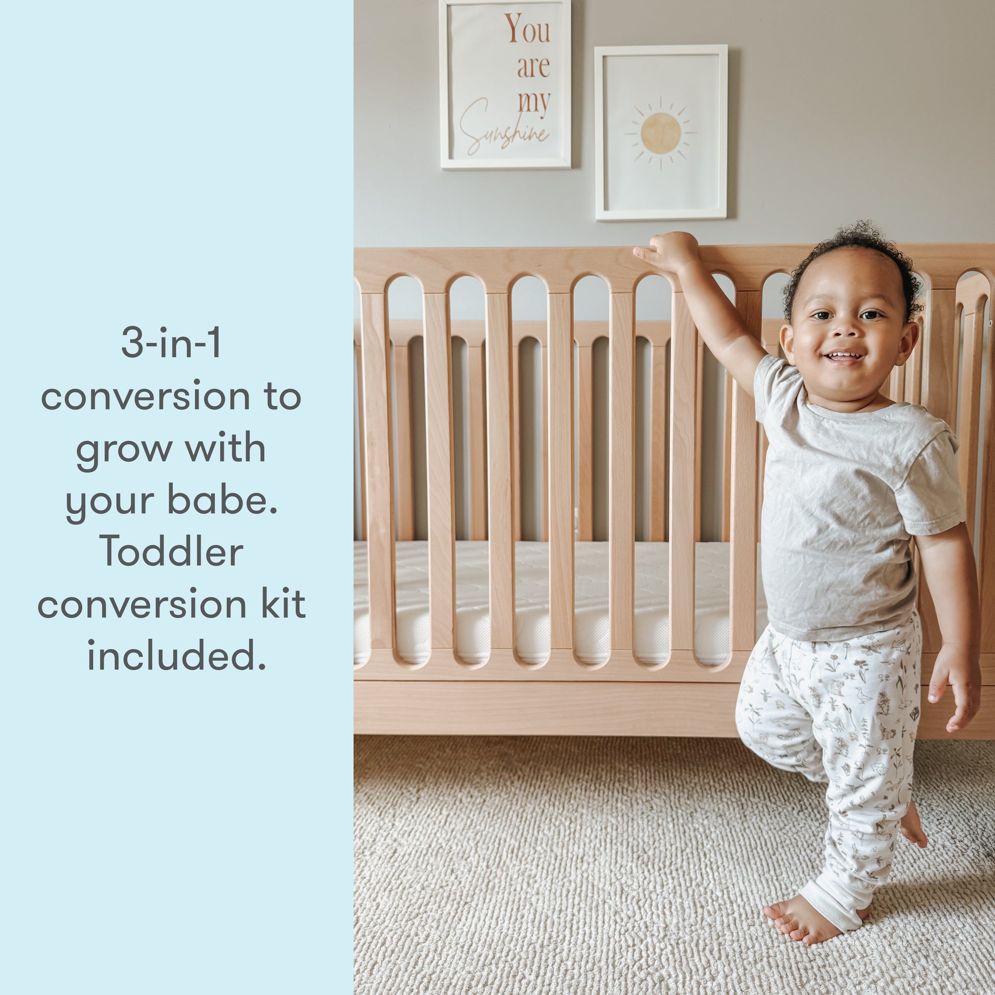 toddler standing next to newton galileo crib in natural color, text reads "3-in-1 conversion to grow with your babe. Toddler conversion kit included."