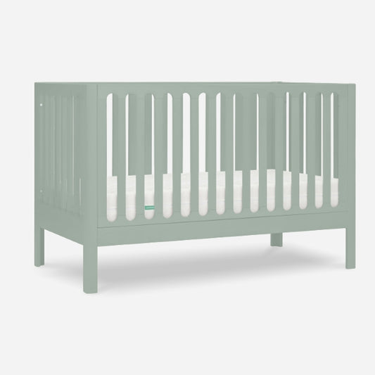 The Newton Galileo Convertible Crib by Newton Baby features a light green finish, vertical slats on all sides, and includes a white mattress. Shown against a plain white background. Toddler bed conversion kit included for long-term use.