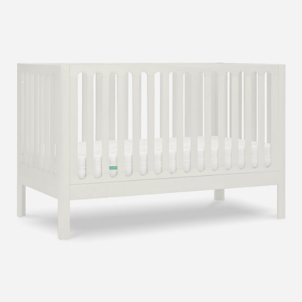 The Newton Galileo Convertible Crib by Newton Baby is a white beech wood crib with vertical slats and a flat base, shown without bedding or decorations against a plain white background.