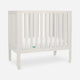 The Newton Baby Galileo Mini Crib with Newton Mattress, featuring vertical slats and four wheels, is crafted from solid Beech wood and shown on a plain white background.