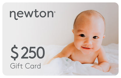 Smiling baby lying on a white blanket promoting a Newton $250 Gift Card. GIFT250