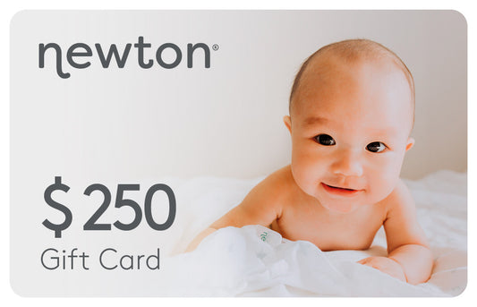 Smiling baby lying on a white blanket promoting a Newton $250 Gift Card. GIFT250