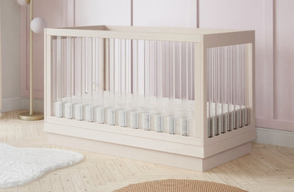 Modern crib in a stylish baby room with light pink walls and wooden flooring.