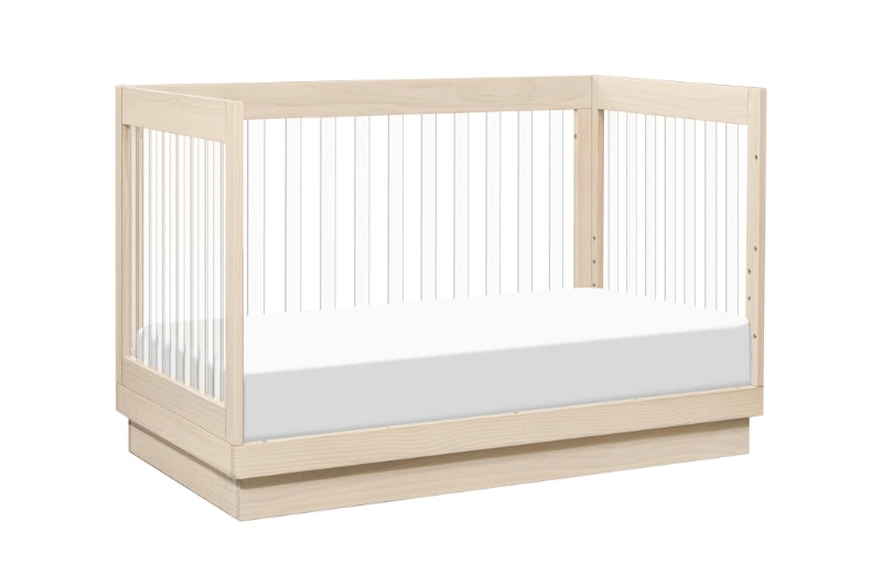 Modern wooden baby crib with a visible white mattress, isolated on a white background.