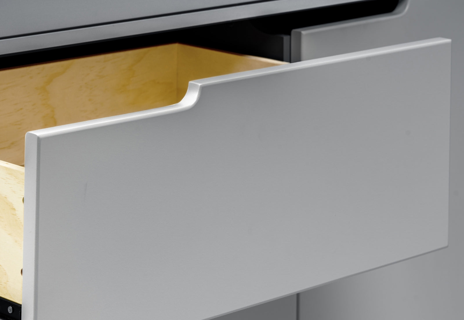 Close-up view of an open white drawer showing its contents and smooth finish ideal for a baby’s room.