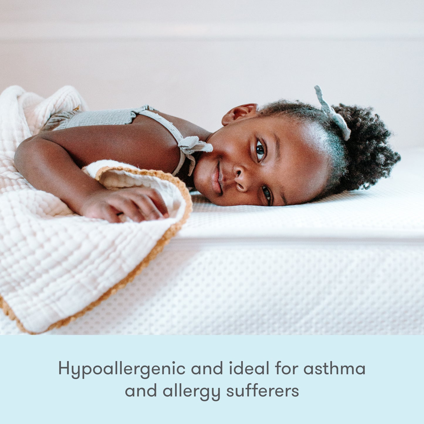 A young child lies comfortably on a bed with a Newton Baby Kids' Twin Mattress. Text at the bottom reads: GREENGUARD Gold certified, hypoallergenic, and ideal for asthma and allergy sufferers.