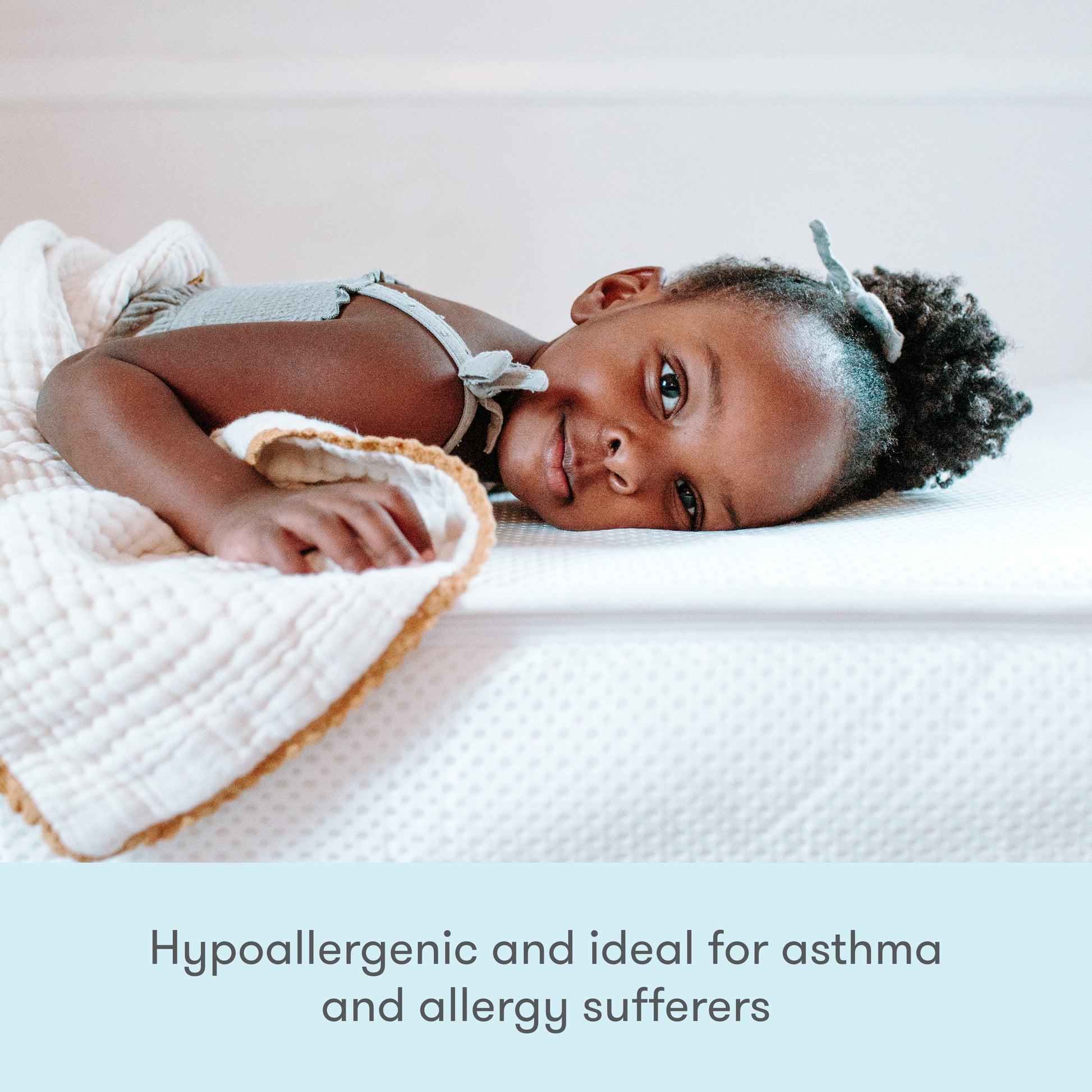 A young child lies comfortably on a bed with a Newton Baby Kids' Twin Mattress. Text at the bottom reads: GREENGUARD Gold certified, hypoallergenic, and ideal for asthma and allergy sufferers.