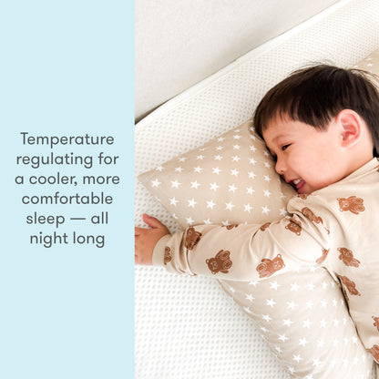 A young child smiling while sleeping on a breathable Newton mattress with a pillow, underneath text stating "Temperature regulating for a cooler, more comfortable sleep — all night long."