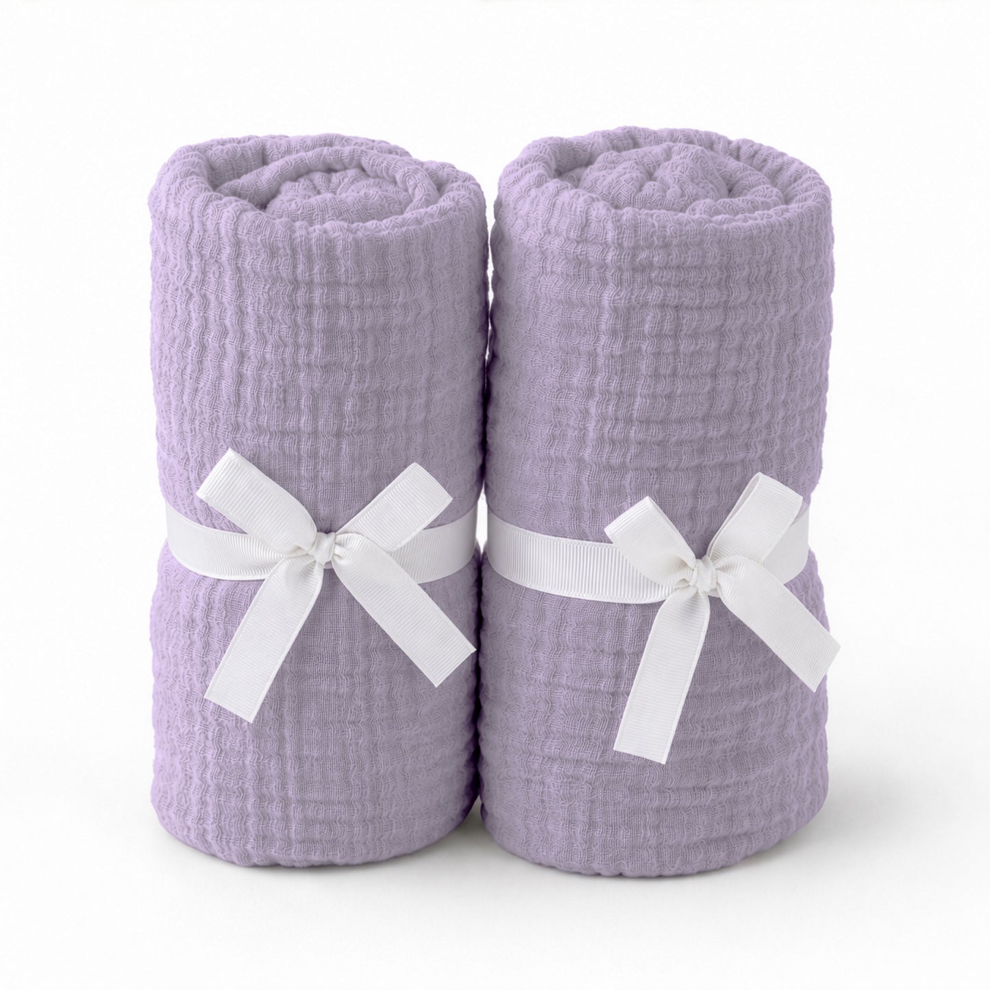 Two rolled, light purple towels with a textured pattern, each tied with a white ribbon bow and placed side by side on a plain white background—evoking the softness of Newton Baby’s Breathable, Organic Cotton Sheets (2-pack).