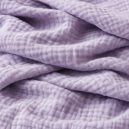 Close-up of soft, textured lavender fabric—like that in Newton Baby’s Breathable, Organic Cotton Sheets (2-pack)—featuring a slightly crinkled surface, subtle grid pattern, and gentle folds.