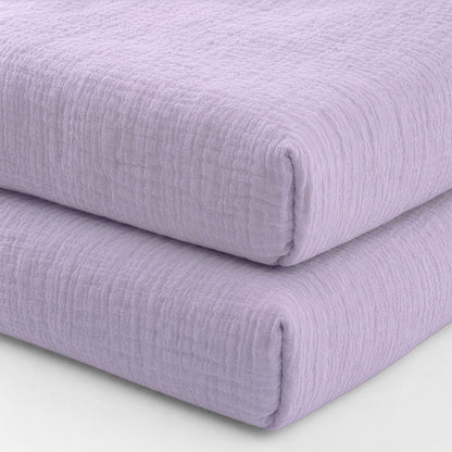 Two breathable, organic cotton sheets (2-pack) by Newton Baby are stacked against a plain white background. Their soft lavender color and textured finish evoke the cozy comfort of premium crib bedding.