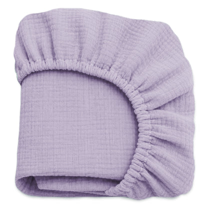 A neatly folded lavender sheet from Newton Baby’s Breathable, Organic Cotton Sheets (2-pack) set, featuring gathered elastic edges and soft muslin cotton, displayed against a white background. 999-3020-LAV