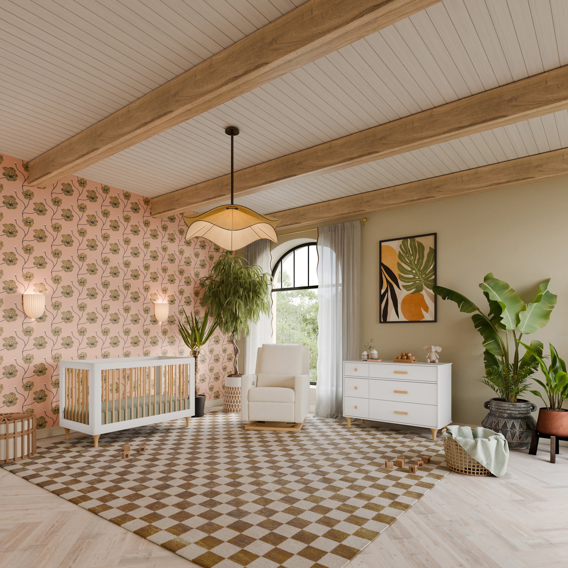 Bright nursery featuring the Babyletto Lolly Convertible Crib crafted from New Zealand pine wood, a cozy rocking chair, dresser, lush plants, and playful wallpaper. Wooden ceiling beams and a checkered rug enhance the modern, inviting space, with toys and a wicker basket arranged on the floor.