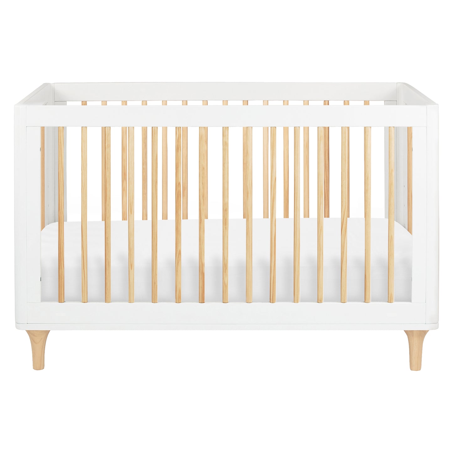The Babyletto Lolly Convertible Crib features a modern design with a white frame, natural New Zealand pine wood slats, and short angled legs. Shown from the front with a fitted white mattress inside, this crib seamlessly blends style and functionality for your nursery.