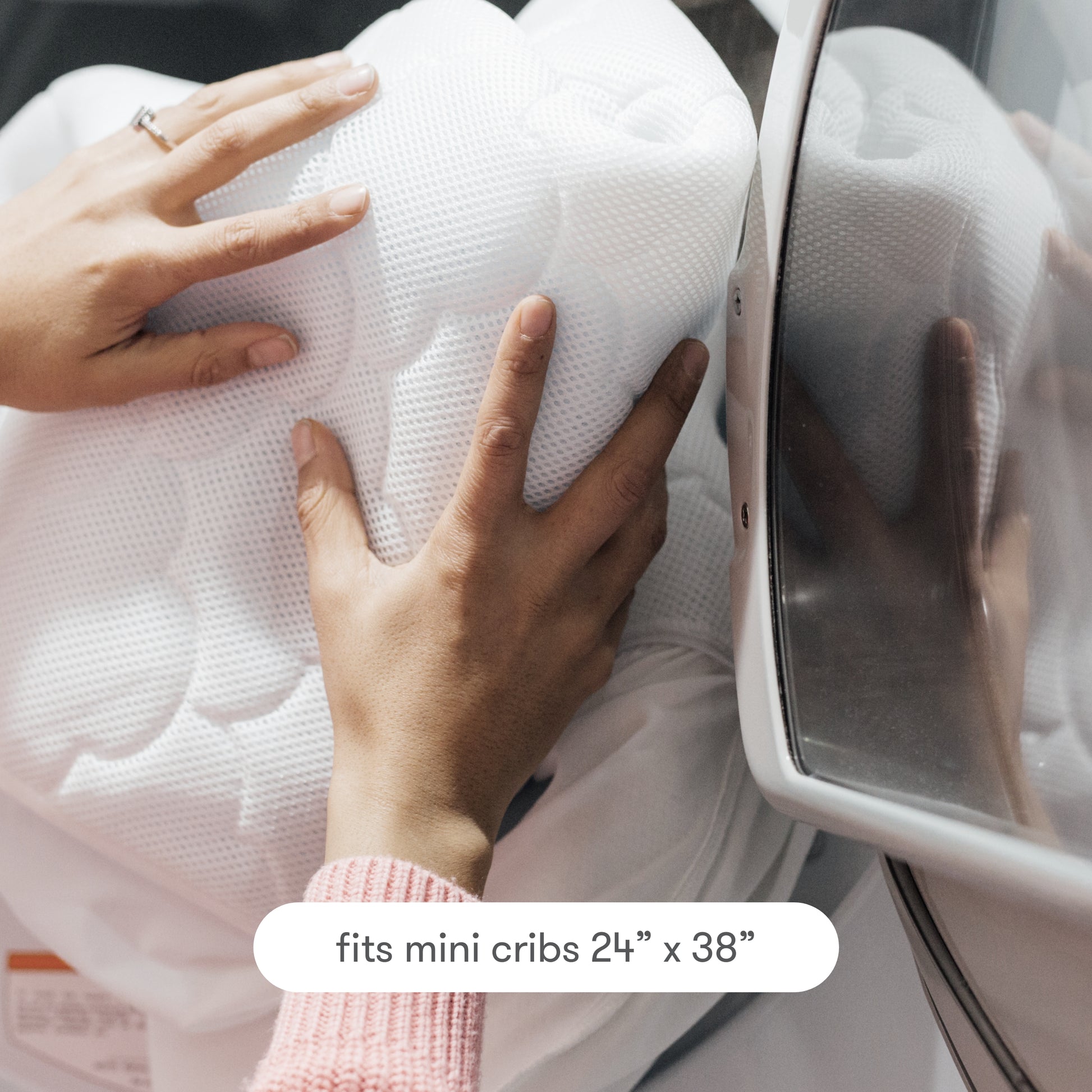 Hands putting the mattress pad in the washing machine, text reads "fits mini cribs 24" x 38""