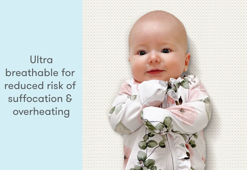 Smiling baby bundled in a floral outfit against a textured background with text: 'Ultra breathable for reduced risk of suffocation & overheating'
