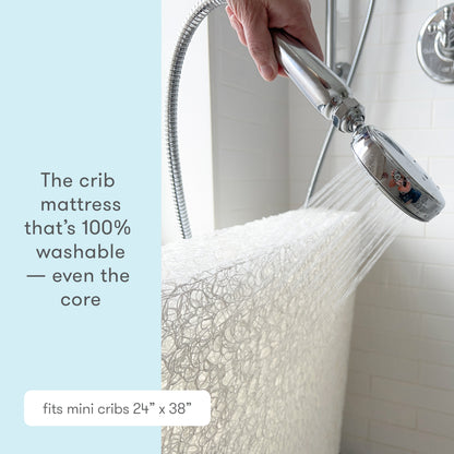 Image of a crib mattress being washed under a showerhead with text that reads, "The crib mattress that's 100% washable — even the core." 