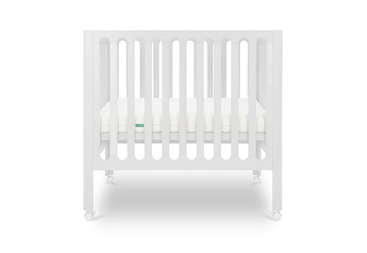 White modern crib on wheels with visible mattress, isolated on a plain background. Mattress in lowered position.