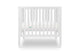 White modern crib on wheels with visible mattress, isolated on a plain background. Mattress in lowered position.