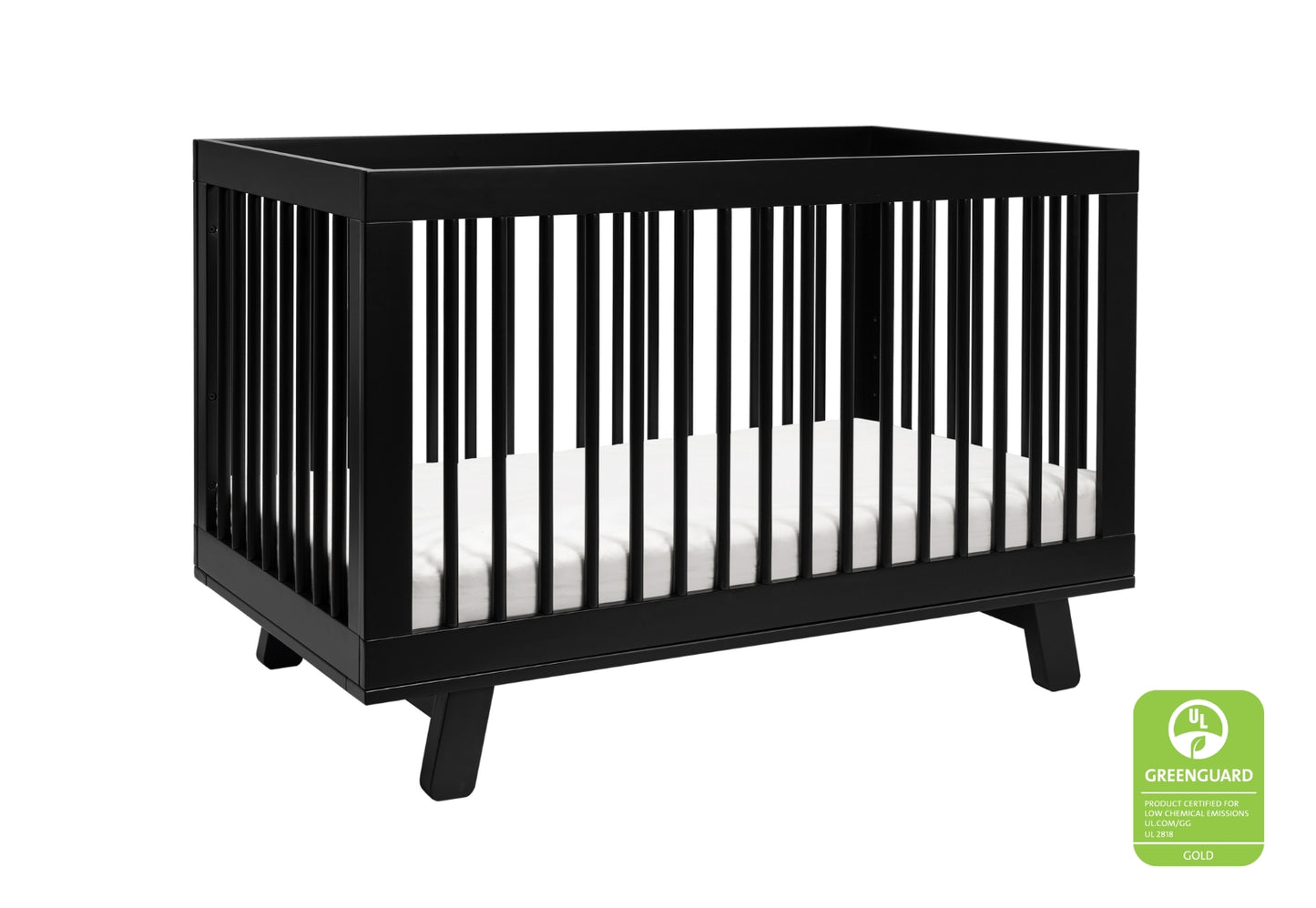 Black wooden crib with a white mattress, featuring the GREENGUARD Gold certification label for low chemical emissions.