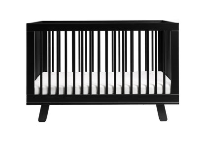 Sleek black modern baby crib with a white mattress isolated on a white background.