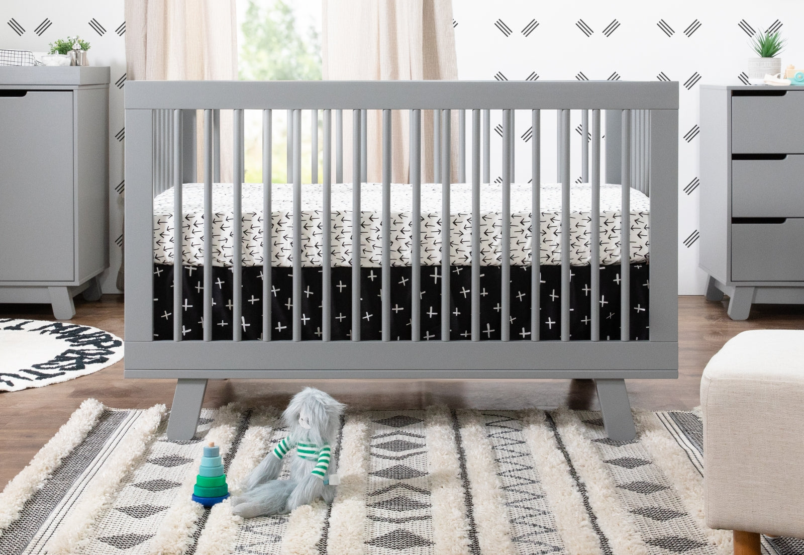 Stylish modern nursery featuring a grey crib with a star-patterned mattress, complemented by geometric decor and a neutral color scheme. 999-8501-GRY